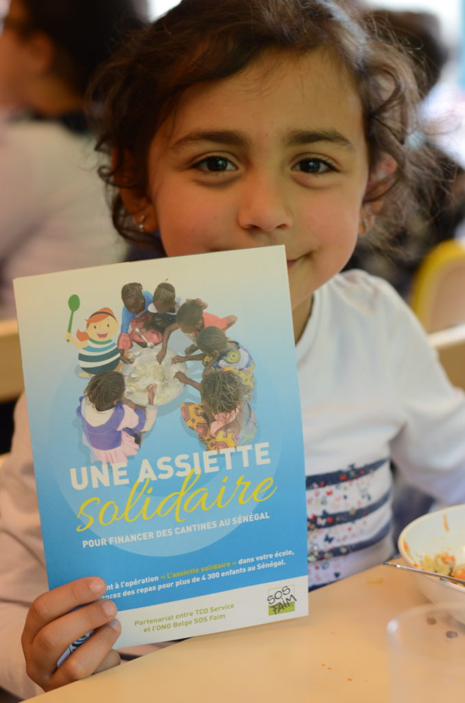 Une élève montrant l’affiche de l’assiette solidaire